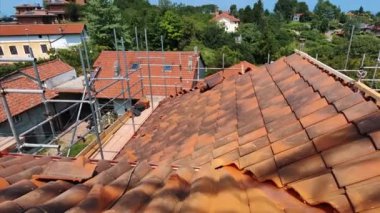 Yerleşim alanı üzerinde çarpıcı bir manzara. Terasotta kaplamalı çatı, yemyeşil ve temiz gökyüzü zeminine karşı iskele ile yenileniyor. Banliyö yaşamını ve ev hayatını tasvir ediyor.