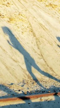 Bir insanın dinamik gölgesi kumlu bir yamaçta belirir, güneş batarken hareket ve sükuneti yakalar. Sakin sahne, özgürlük ve macera duygusunu çağrıştırıyor..