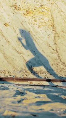 Bir insanın dinamik gölgesi kumlu bir yamaçta belirir, güneş batarken hareket ve sükuneti yakalar. Sakin sahne, özgürlük ve macera duygusunu çağrıştırıyor..