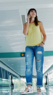 Crossing, konuşurken, ona telefon, iletişim, ortalaması kullanarak metro otomatik yürüyüş yolları arasında yürüyen kadın Gadget'ı. Her zaman temas halinde bir kavramdır