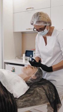 Beauty therapy. facial massage. Cosmetology skin care. beautician, in medical mask and gloves, performs cosmetic skincare facial scrubbing procedure, at beauty clinic. anti-aging. facial rejuvenation.