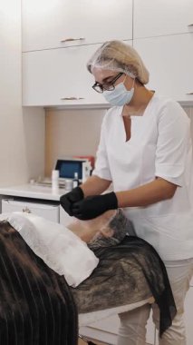 beauty therapy. facial massage. Cosmetology skin care. beautician, in medical mask and gloves, performs facial skincare massage for woman, at beauty clinic. anti-aging procedure. Facial rejuvenation