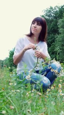 Ormanda, genç bir kadın, esmer bir kadın papatya çelengi örüyor.