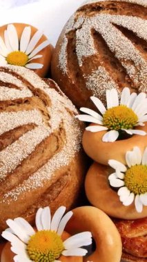 Beyaz papatyalarla süslenmiş hamur işleri, bisküviler ve kurabiyelerle dolu beyaz tabak. Beyaz çay tabağında iki beyaz fincan ve papatya çayı var.