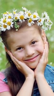 Papatya çimenlikte, tatlı bir kız gülümsüyor, papatyalar, çelenk içinde elleri onun yanakları için basarak