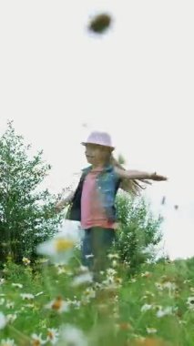 Çim, çayırda, dans, Zıplama, eğlenceli, güzel bir kız, yaklaşık yedi yaşında sahip papatyalar arasında. Uzun sarı saçlı, kot yelek ve pembe şapka giymiş