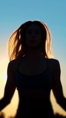 Şekil, anahat uzun sarı saçlı bir güzel, atletik kız yaz aylarında güneş ışığı altında mavi gökyüzü günbatımı, ip atlama.