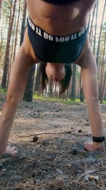 Koç fitness sistemi ile egzersiz yapıyor, süspansiyon kayışları. Çam ormanlarında, yazın, güneş ışınlarında. Aşağıdan bak, şınav çek.