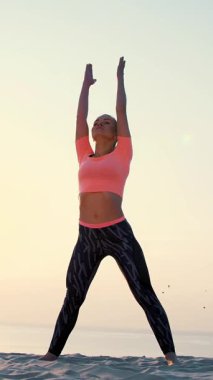 Sağlıklı, genç güzel kadın meditasyon, germe, pratik yoga deniz plajda güneş doğarken, denge ve koordinasyon, derin Kas tonusu için egzersizler yapar