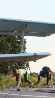 Legs.on uçak yakın terk edilmiş bir uçak pisti kaldırma zaman uyumlu olarak farklı güç egzersizleri, atlar, şınav, tayt, güneş gözlüğü güzel, atletik, genç kadınlarda gerçekleştirmek