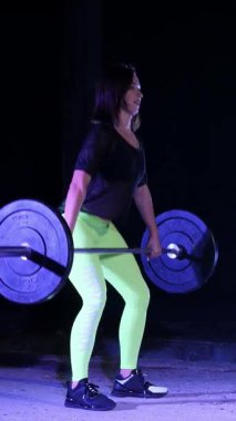 atletik genç kadın, halter yükseltir, halter ile mekik yok. Geceleri, projektörler, hangarda bir eski terk edilmiş, Bina hafif duman, sis ışığında