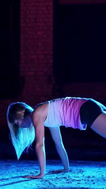 atletik, seksi bir kadın fitness trx sistemi, Trx askı kayışları ile çalışmaları gerçekleştirir. Gece, çok renkli projektörler, ışığında hafif duman, sis içinde binayı terk.