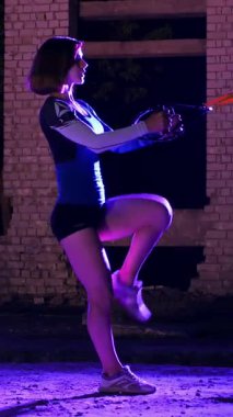 Atletik kadın spor yapıyor spor sistemi, süspansiyon kayışları. Geceleri, hafif dumanlarda, siste, çok renkli projektörlerde, terk edilmiş binada.