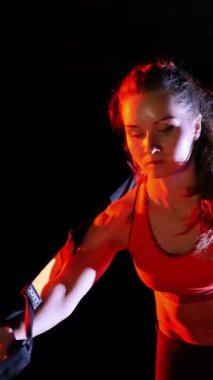Atletik kadın spor yapıyor spor sistemi, süspansiyon kayışları. Geceleri, hafif dumanlarda, siste, çok renkli projektörlerde, terk edilmiş binada.