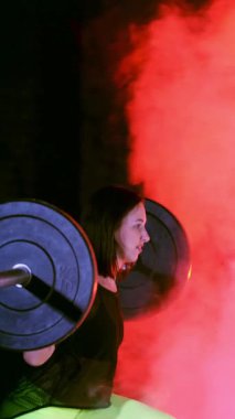 Atletik genç bir kadın, halteri kaldırıyor, halterle mekik çekiyor, onun için zor. Geceleri, çok renkli projektörlerin ışığında, hafif dumanlarda, sislerde, terk edilmiş eski binada