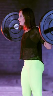 Atletik genç bir kadın, halteri kaldırıyor, halterle mekik çekiyor, onun için zor. Geceleri, çok renkli projektörlerin ışığında, hafif dumanlarda, sislerde, terk edilmiş eski binada