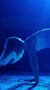 Atletik kadın spor yapıyor spor sistemi, süspansiyon kayışları. Geceleri, hafif dumanlarda, siste, çok renkli projektörlerde, terk edilmiş binada.