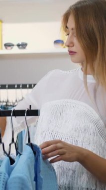 İş kadını mağazada kıyafet seçer. Şık bir giyim mağazasından alışveriş yapmak. yavaş çekim