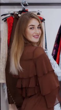 İş kadını mağazadan kıyafet seçer, aynanın karşısında kendine hayran kalır, gülümser. Şık bir giyim mağazasından alışveriş yapmak. yavaş çekim