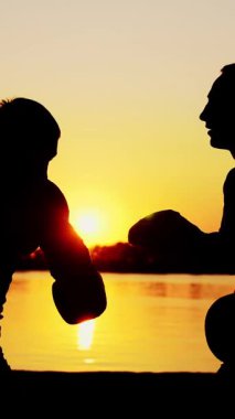 İki siyah erkek figürü, gün doğumunda, ışığa karşı, boks, dövüş, yaz aylarında, su kenarında, bir çift grev teknikleri eğitimi.