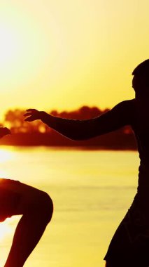 İki siyah erkek figürü, gün doğumunda, ışığa karşı, boks, dövüş, yaz aylarında, su kenarında, bir çift grev teknikleri eğitimi.