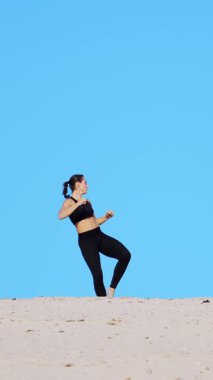 atletik kız siyah bir üst ve tozluk, uygulama başladı, ayak, savaşmak eğitim gölge ile mücadele başladı. Issız kumsalda, mavi gökyüzü, sıcak güneşin altında yaz aylarında karşı.