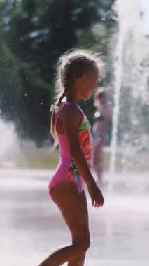 Mayo, yedi yıllık bir kız çeşme banyo, etrafında koşmak, ufaklık, iyi eğlenceler, sıcak yaz gününde. Ağır çekim