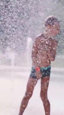 Çocuk çeşme arasında eğleniyor, etrafta koşuyor, serpiyor, eğleniyor, eğleniyor, sıcak bir yaz gününde..