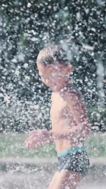 Çocuk çeşme arasında eğleniyor, etrafta koşuyor, serpiyor, eğleniyor, eğleniyor, sıcak bir yaz gününde..