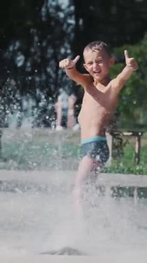 Çocuk çeşme arasında eğleniyor, etrafta koşuyor, serpiyor, eğleniyor, eğleniyor, sıcak bir yaz gününde..