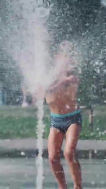 Çocuk çeşme arasında eğleniyor, etrafta koşuyor, serpiyor, eğleniyor, eğleniyor, sıcak bir yaz gününde..