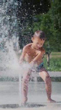 Çocuk çeşme arasında eğleniyor, etrafta koşuyor, serpiyor, eğleniyor, eğleniyor, sıcak bir yaz gününde..