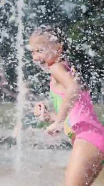 Mayolu bir kız, çeşmede yıkanan, etrafta koşuşturan, fışkırtan, eğlenen, sıcak bir yaz günü. Yavaş çekim