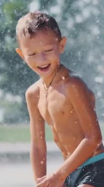 Yedi yaşında bir çocuk, sıcak bir yaz gününde çeşmede banyo yapıyor ve dışarıda su sıçratmaca oynuyor. Yavaş çekim