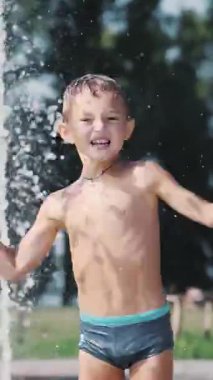 Yedi yaşında bir çocuk, sıcak bir yaz gününde çeşmede banyo yapıyor ve dışarıda su sıçratmaca oynuyor. Yavaş çekim