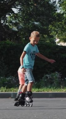 Mutlu çocuk, yedi, paten, sıcak bir yaz günü, iki erkek. Ağır çekim.