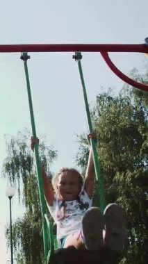 Mutlu çocuk, bir kız ve bir erkek yedi, sıcak bir yaz günü bir salıncağa binmek. Ağır çekim. Mutlu çocukluk, tatil