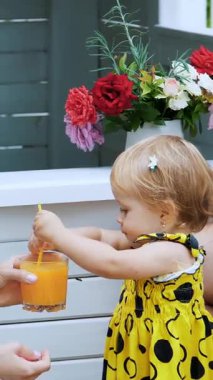 Ebeveynler küçük çocuklarla oynuyorlar, bir kız ve bir erkek, bir kafede, bir çocuk oyun evinde, çocuklara taze sıkılmış meyve suyu ile davranıyorlar, meyve suyu içiyorlar..