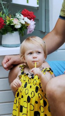 Ebeveynler küçük çocuklarla oynuyorlar, bir kız ve bir erkek, bir kafede, bir çocuk oyun evinde, çocuklara taze sıkılmış meyve suyu ile davranıyorlar, meyve suyu içiyorlar..