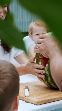 Yaz aylarında Bahçe, bir akşam yemeği masada oturan iki küçük komik çocuklu genç bir aile. Babam büyük bir karpuz keser, ailesi tedavi edecek. Aile ile yemek.