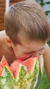 Dört yaşında bir oğlu olan baba bir karpuz keser ve yer, eğlenir, bir çocuk karpuzu çok sever. Aileyle öğle yemeği için tatlı karpuz.