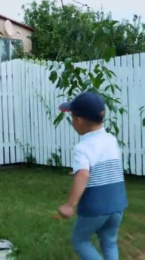 çıplak ayakla çimlerde, avlunun bir yeşil çim üzerinde yaz aylarında joggling dört yaşındaki çocuk. Güler, eğlenir