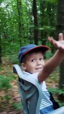 bir kadın bir şapka ve çiçekler, küçük çocuk, birlikte bir sepet ile elbise yaz aylarında ormandaki Bisiklet binmek. Çocuk özel bir sandalyede oturuyor