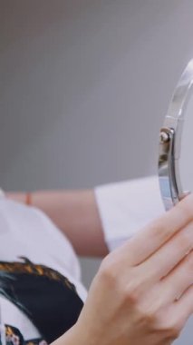 Doktor hastaya bir ayna sunuyor, dudak büyütme prosedürünü hyaluronik asitle tartışıyor. Klinik, kozmetoloji odası..