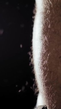 Saç kesimi. Kıllılık. Yakın plan. Eldivenli el, erkek mide kıllarını elektrikli saç makası ve makineyle keser. Alacakaranlıkta erkek saç kesimi prosedürü, ışık ışınları. Vücut bakımı