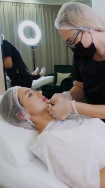 Doktor, dudak büyütme ameliyatından sonra hastaya hyaluronik asit enjeksiyonları hakkında danışır..