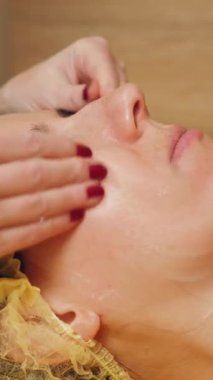 Kozmetoloji, yüz temizleme. Kadınlar için kozmetik prosedürler. Yakın plan. Kadın kanepede uzanıyor ve güzellik kliniğinde yüz temizleme ameliyatı oluyor. Cilt bakımı, cilt bakımı.