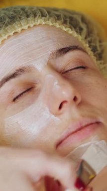 Kozmetik yüz maskesi. Yakın plan. Kadın kanepede uzanıyor ve güzellik kliniğinde yüz bakımı yaptırıyor. Cilt bakımı, cilt bakımı.