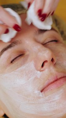 Kozmetoloji, yüz temizleme. Kadınlar için kozmetik prosedürler. Yakın plan. Kadın kanepede uzanıyor ve güzellik kliniğinde yüz temizleme ameliyatı oluyor. Cilt bakımı, cilt bakımı.