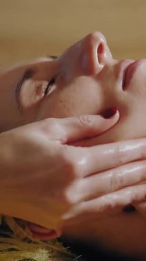 Yaşlanma önleyici prosedür, yüz masajı. Yakın plan. Kadın kanepede uzanıyor ve yüz masajı yaptırıyor. Güzellik kliniğinde yüz ve yüz derisi kanalizasyonu için. Cilt bakımı, kozmetoloji. Kadınlar için kozmetik prosedürleri.